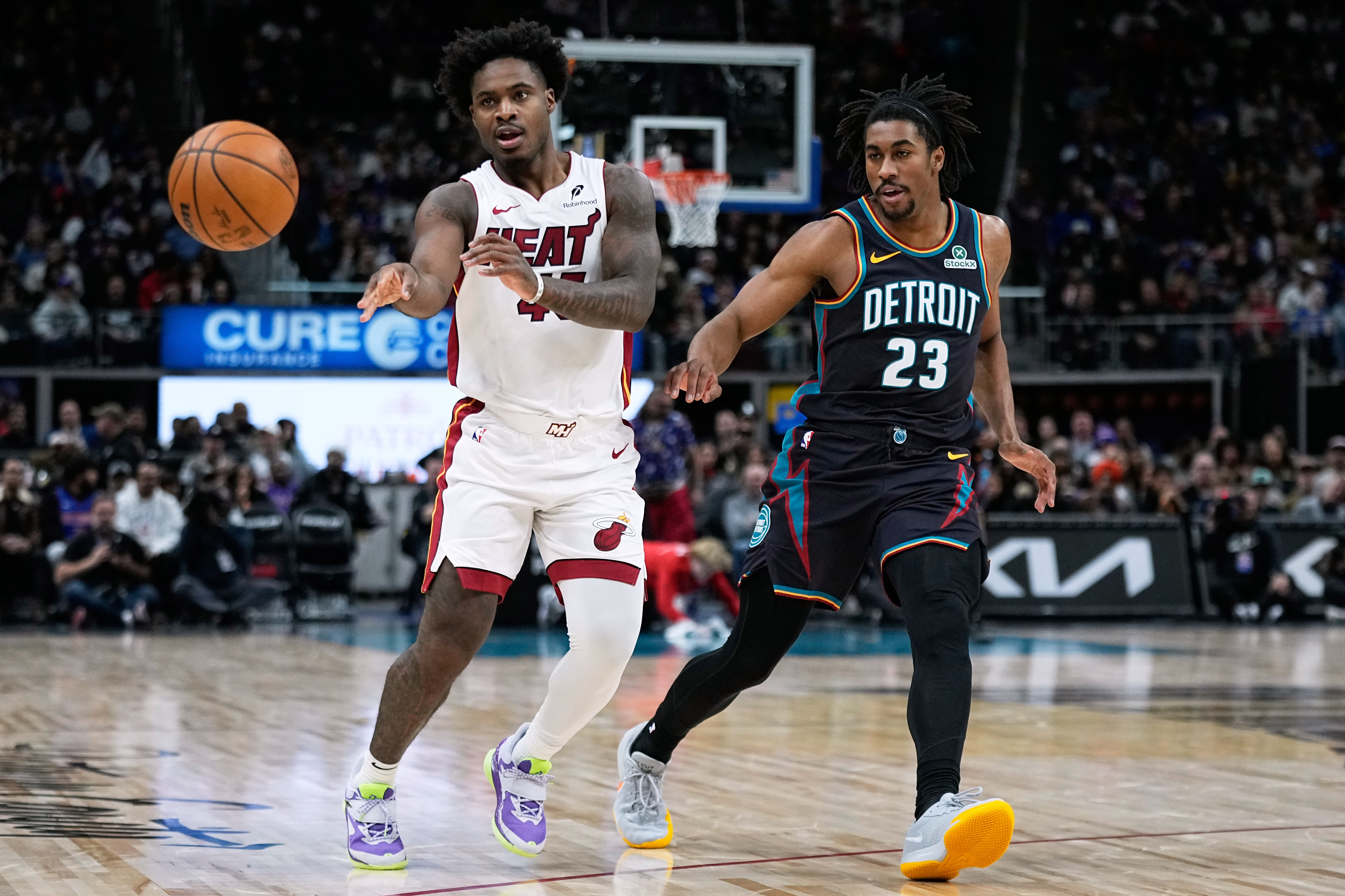 Miami Heat guard Davion Mitchell, left, passes past Detroit Pistons guard Jaden Ivey during the first half of an NBA basketball game, Thursday, Jan. 1, 2026, in Detroit. (AP Photo/Ryan Sun)