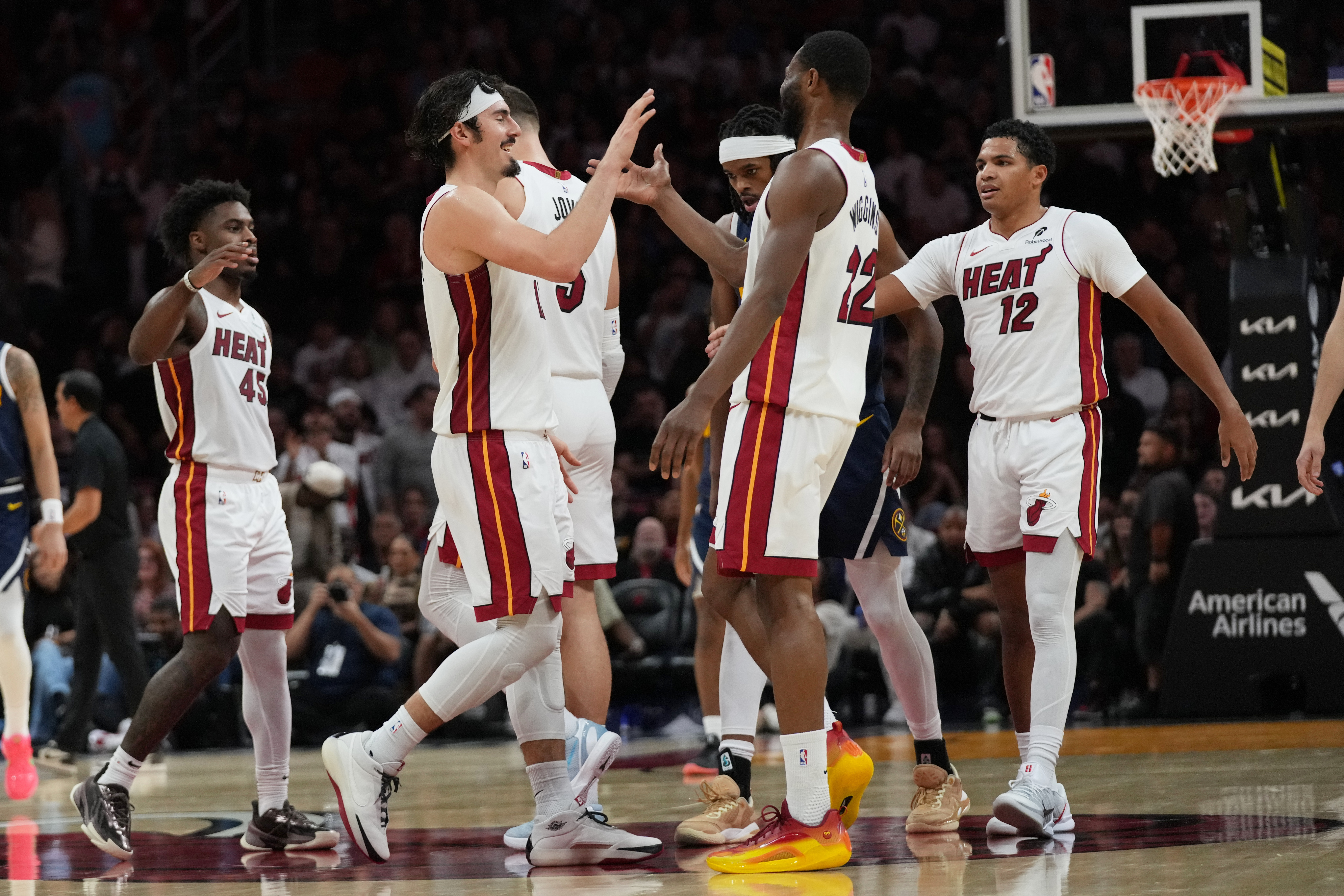 Miami Heat forward Jaime Jaquez Jr., second from left, forward Andrew Wiggins (22) and guard Dru Smith (12) high-five during the second half of an NBA basketball game against the Denver Nuggets, Monday, Dec. 29, 2025, in Miami. (AP Photo/Lynne Sladky)