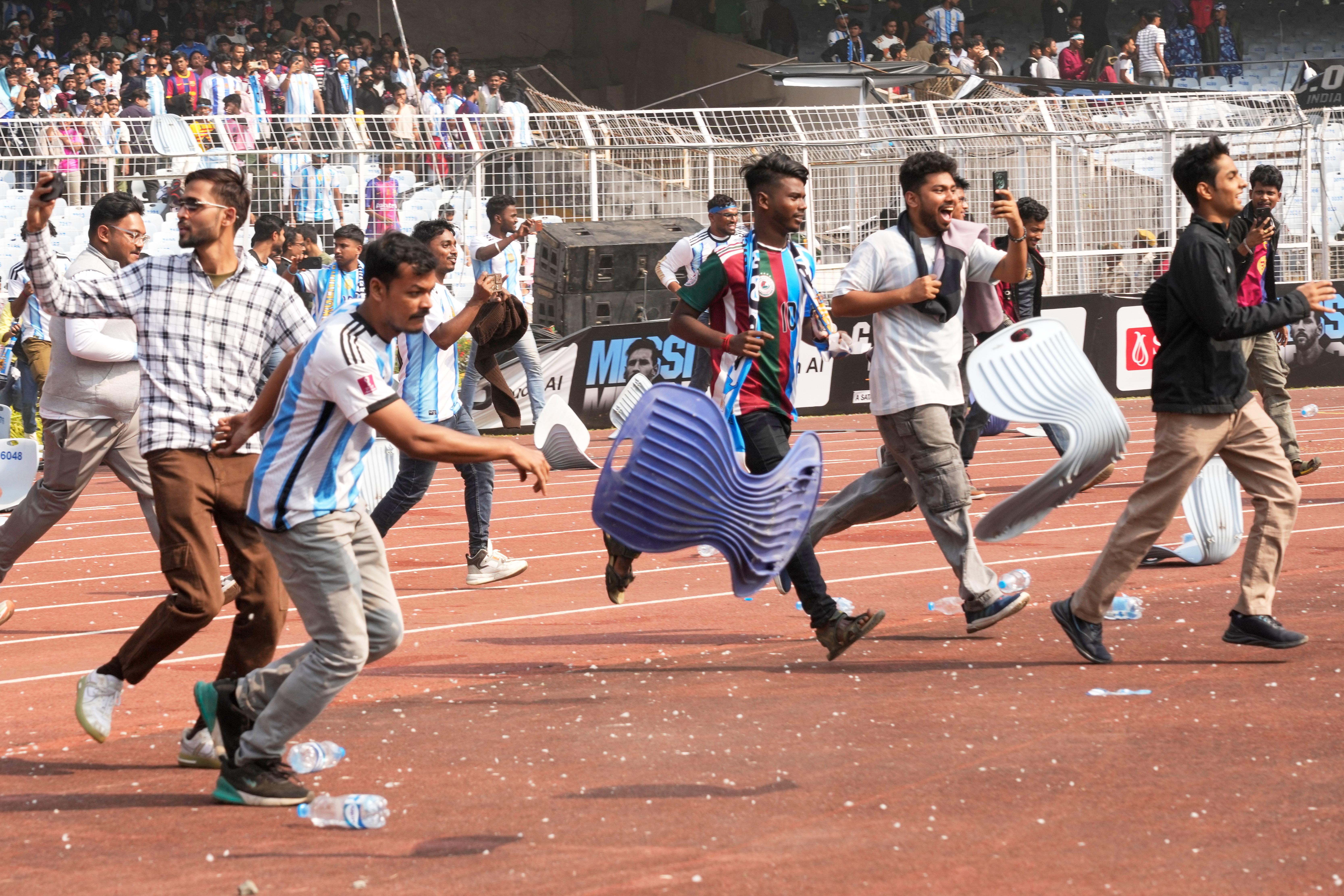 Indian fans vandalize stadium chairs as they run on to the field after failing to get a glimpse of Argentine soccer star Lionel Messi at the Salt Lake Stadium, in Kolkata, India, Saturday, Dec. 13, 2025. (AP Photo/Bikas Das)

