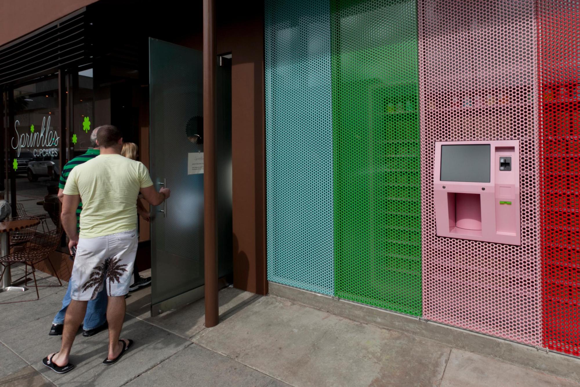 FILE – A newly-installed 24-Hour Cupcake “ATM,” that will be continuously restocked to dispense fresh cupcakes, is seen right as patrons enter Sprinkles Cupcakes in Beverly Hills, Calif., March 5, 2012. (AP Photo/Damian Dovarganes, File)
