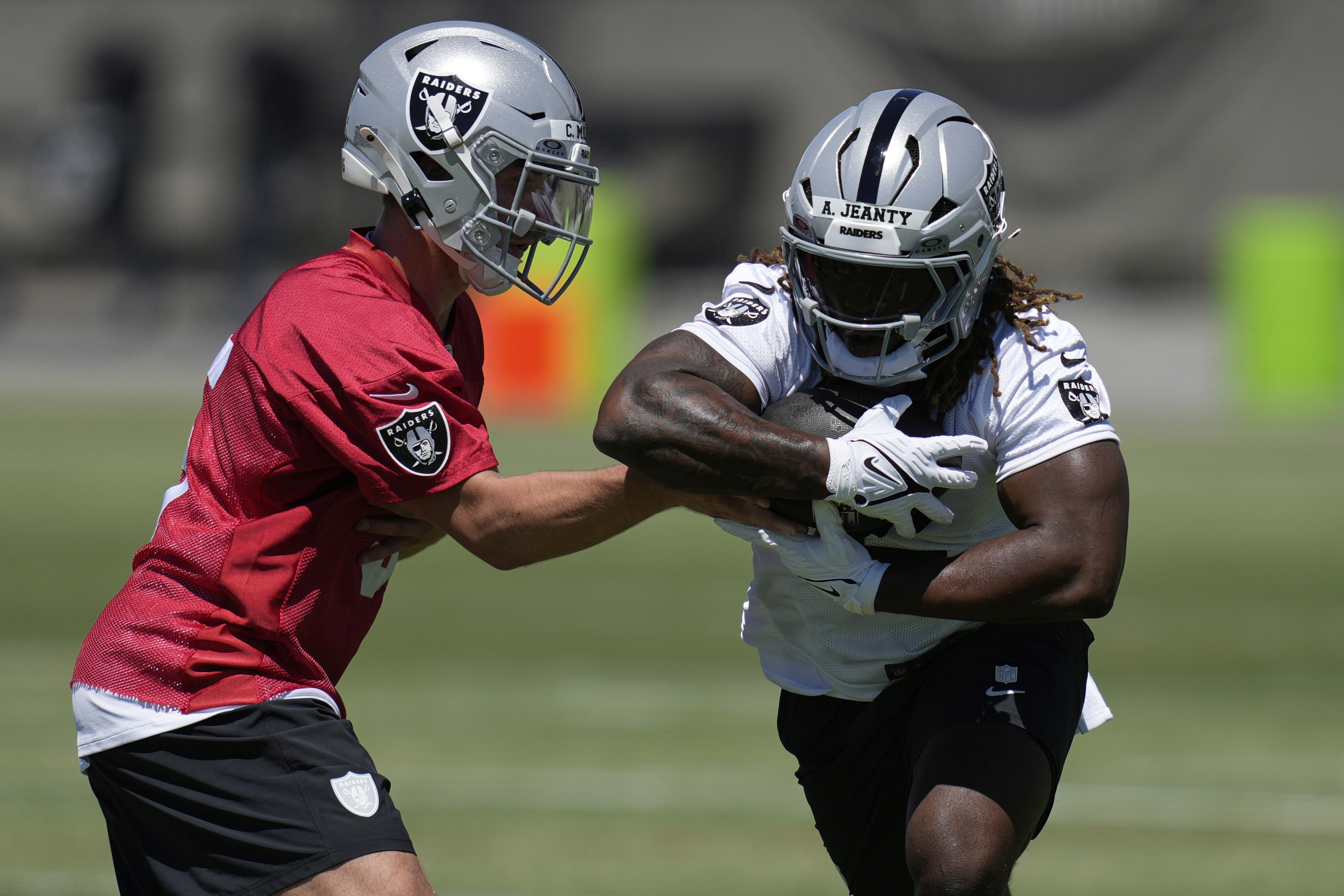 Las Vegas Raiders' quarterback Cam Miller hands off a ball to Ashton Jeanty during a rookie mini camp on May 9, 2025, in Henderson, Nev. (AP Photo/John Locher)