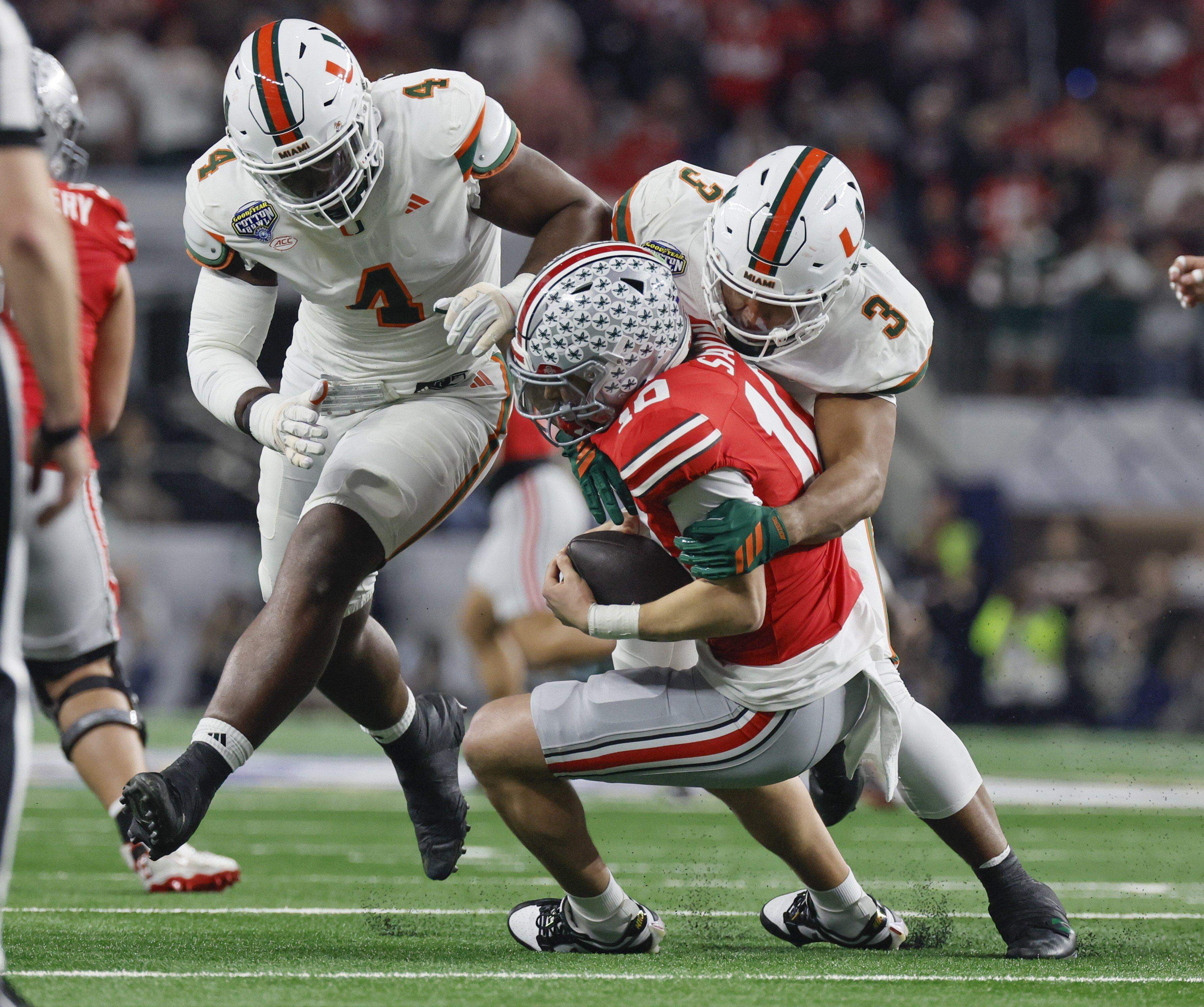 Miami Hurricanes defensive lineman Rueben Bain Jr. (4) and defensive lineman Akheem Mesidor (3) sack Ohio State Buckeyes quarterback Julian Sayin (10) during the first half of the College Football Playoff quarterfinal game in the Cotton Bowl in Arlington, Texas on Wednesday.